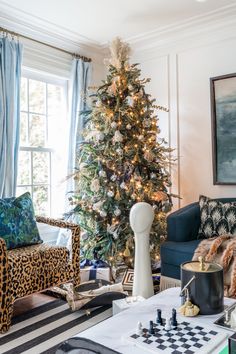 a living room with a christmas tree and chess pieces on the coffee table in front of it