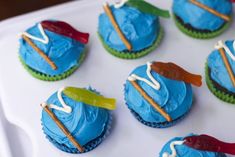 cupcakes decorated with blue frosting and colorful toppings on a white tray