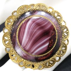 *Description: This is a beautiful Western Germany purple slag glass brooch with a filigree frame from the 1950s or late 1940s. The brooch is stamped on the clasp WESTERN GERMANY. One of the unique features of this brooch is there is a glass center framed in metal, then set in another round glass and then set in a filigree frame. This would be a great addition to your vintage jewelry collection or make a great vintage gift! *Approximate Measurements: Length & Width - 1 7/8 Inches, Weight - .6 Mid-century Cabochon Brooch For Gift, Mid-century Cabochon Brooch Gift, Mid-century Cabochon Brooches For Gifts, Vintage Filigree Brooches For Formal Occasions, Collectible Vintage Round Brooches, Vintage Cabochon Brooch For Wedding, Vintage Cabochon Brooches For Wedding, Vintage Filigree Brooches, Vintage Wedding Brooches With Cabochon