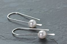 Simple, pretty, minimalist threader earrings in Sterilng Silver wire with white Swarovski pearls. These earrings are hand formed sterling silver ear wires that have a hammered paddle end.  The earrings hang 1 1/4 inches (3.1 cm) long. Made with Argentium Sterling Silver that is bright and tarnish resistant. These Pearl beads are Swarovski made in Austria. **Also available in silver with rose gold, and grey pearls. All earrings come with clear earring stoppers. All of my designs are created by me Minimalist Pearl Drop Threader Earrings, Minimalist Wire Wrapped Pearl Drop Earrings, Delicate Pearl Earrings With Ear Wire In Sterling Silver, Delicate Sterling Silver Pearl Earrings With Ear Wire, Minimalist Wedding Threader Earrings With Ear Wire, Minimalist White Threader Earrings For Everyday, Minimalist Threader Earrings With Ear Wire For Wedding, Handmade Minimalist Pearl White Pearl Earrings, Everyday White Pearl Drop Threader Earrings