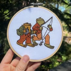 someone is holding up a small embroidery hoop with an image of two bears on it