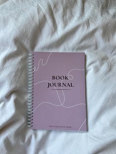 a book that is laying on top of a white bed sheet with the words book journal written in cursive writing