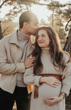 a man and woman standing next to each other in front of trees with the sun shining on them