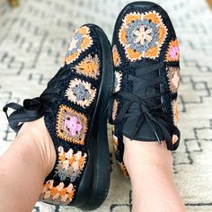 a woman's feet wearing black sneakers with colorful crochet