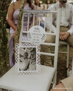 a photo frame sitting on top of a white chair next to a tree and people