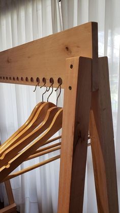 a wooden coat rack with clothes hanging from it's hooks and hangers in front of a window