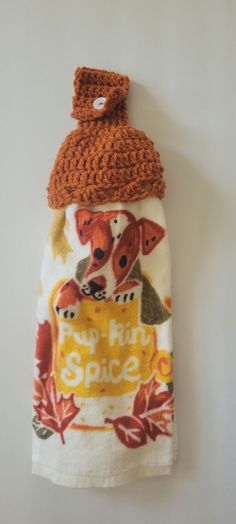 a small towel hanging on the wall with a knitted hat on top of it