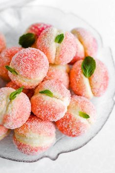 powdered sugar coated donuts on a glass plate with mint sprigs and leaves