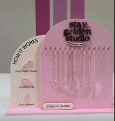 a pink stand with some earrings hanging from it's sides and the words stay golden studio on it