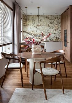 a dining room table with chairs and a vase filled with flowers on top of it