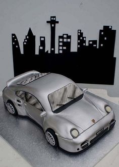 a silver toy car sitting on top of a white surface next to a city skyline