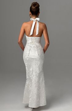 the back of a woman wearing a white dress with a bow at the neckline