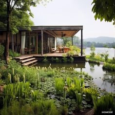 a house sitting on top of a lush green hillside next to a lake with lily pads