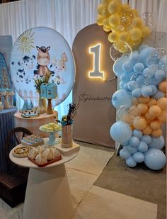 a table topped with balloons and desserts next to a sign that says 1st birthday