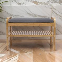 a wooden bench sitting on top of a hard wood floor next to a marble wall