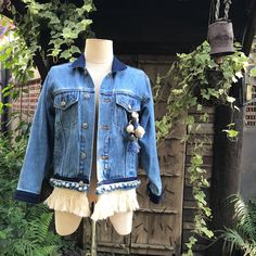 "Arya is from our Denim & Textile Collection. Up-cycled denim jacket embellished with fringe, pom-poms, and Thai textiles. Size: Women's Medium Measurements:   Shoulders  15\"      Bust  38\" Waist 34\" Sleeves 19\"" Bohemian Cotton Denim Jacket With Frayed Hem, Bohemian Denim Jacket With Frayed Hem, Denim Outerwear With Frayed Hem For Festival, Spring Denim Jacket With Beaded Fringe And Long Sleeves, Casual Denim Jacket With Frayed Hem For Festivals, Casual Cotton Outerwear With Tassels, Textile Collection, Womens Jackets, Pom Poms