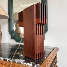 a wooden lamp sitting on top of a table next to a mirror and lampshade