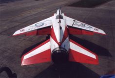 a red and white jet sitting on top of an airport tarmac