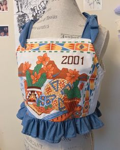 a mannequin wearing a blue and white apron with an image of flowers on it