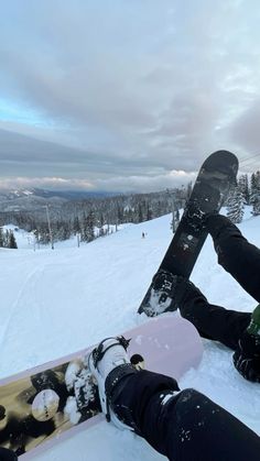 a snowboarder is sitting in the snow with his feet propped up on their board