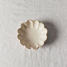 a small white bowl sitting on top of a white cloth covered table next to a knife and fork