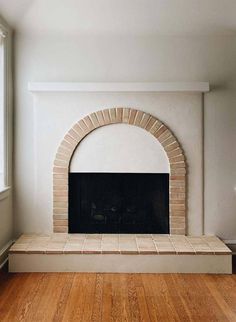 an empty living room with a fireplace and hardwood floors