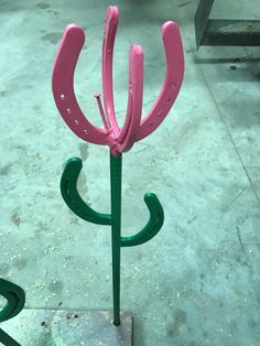 a pink flower sitting on top of a metal stand next to a green planter