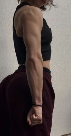 a woman standing in front of a white wall with her hands on her hips and looking at the camera