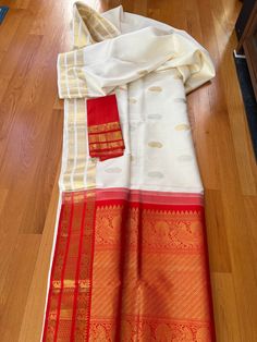 Exquisite Kanjiwaram Silk White and Red saree. Classic combination, it has silver gold zari,  ravishing border with peacock and rudraksh motif.   SILK MARK CERITIFIED  This Saree is ready to wear with fall and pico done.  Note. This is a handwoven saree and there might be slight inconsistency such as in it's weaving. White Handloom Traditional Wear For Rituals, Traditional White Saree For Rituals, Elegant Saree For Navratri Rituals, Elegant Saree For Rituals And Festivals, White Dupatta With Traditional Patterns For Rituals, Elegant Dupatta With Zari Weaving For Rituals, White Traditional Wear With Traditional Patterns For Rituals, White Saree With Traditional Drape For Rituals, White Cutdana Saree For Rituals