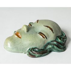 a ceramic sculpture of a woman's head with eyes closed and hair curled up