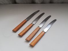 four knives are lined up on a table