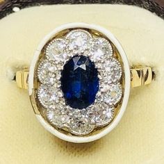 An unusual and impressive example of an Art deco Sapphire and Diamond cluster ring. with a halo of white enamel. The central sapphire measures 75 points, each surrounding Old European Cut diamond measures 10 points. Wonderful item.CONDITION: See photos. Some damage to enamel. RING SIZE: N UK 6 3/4 USWEIGHT: 4.4 gramsNO RESERVE!Payment with Paypal. We offer large shipping reductions on multiple purchases, please get in touch for a quote!OFFICE USE ONLY: UDZZ 10 Points, Enamel Ring, European Cut Diamonds, Diamond Cluster Ring, Diamond Cluster, White Enamel, Cluster Ring, Rings Statement, Sapphire Ring