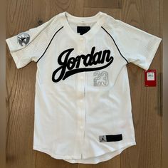 Air Jordan Baseball Youth Jersey Size L Black And White Button Down 75% Polyester 25% Elastane Measures 17in Across Chest And 27in Back Of Shirt Neck To Bottom Hem Sporty White Top With Baseball Collar, White Cotton Tops With Baseball Collar, White Baseball Collar Top For Streetwear, White Tops With Baseball Collar For College, White Fitted Baseball Jersey For College, College Fitted White Baseball Jersey, White Tops With Graphic Print And Baseball Collar, Casual White Baseball Jersey With Baseball Collar, White Casual Baseball Jersey For Streetwear