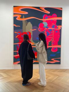 two people standing in front of a large painting