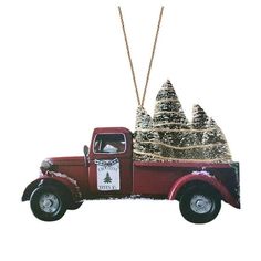 an ornament with a red truck and trees in the back is hanging on a chain