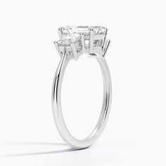 a three stone diamond ring on a white background