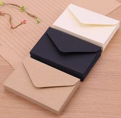 three envelopes sitting on top of each other next to some papers and a flower