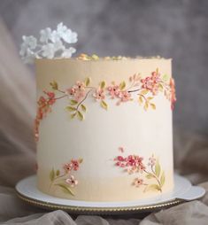 a white cake with pink and yellow flowers on it sitting on a plate next to tulle