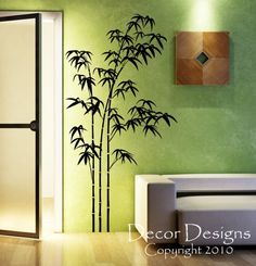 a living room with green walls and bamboo tree decal on the wall, next to a white couch