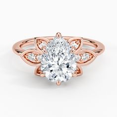 a rose gold engagement ring with a pear shaped diamond in the center and side stones