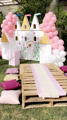 a table with pink and white balloons on it in front of a fairy castle backdrop