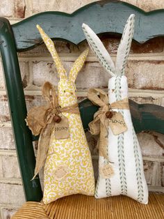 two stuffed bunnies sitting on top of a wooden chair