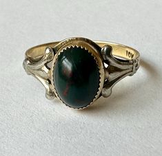 a vintage, likely antique, gold pinky ring with a bloodstone cabochon.  the ring is 10k gold with white gold embellishments on the shoulders.  the bloodstone is very dark green with red swirls.  it has some tiny blemishes and one bigger scratch, hard to see because the stone is so dark and small.  has been sized, very hard to tell from the outside, and has reasonable wear. size:  4.25 height of face:  a bit over 5/16" width of inner band:  1/16" weight:  1.2g Very Dark Green, Gold Pinky Ring, Gold Embellishment, Pinky Ring, 10k Gold, Rings Statement, Antique Gold, Statement Rings, To Tell