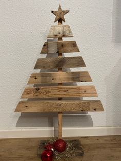 a wooden christmas tree with red ornaments on the bottom and one star hanging from it