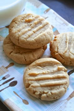 three peanut butter cookies sitting on top of a table next to a glass of milk