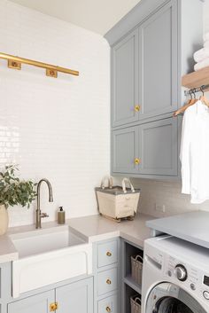 a washer and dryer in a room with white tile on the walls, blue cabinets