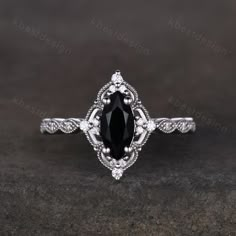 an oval black diamond engagement ring with filigrees on the sides and shoulders