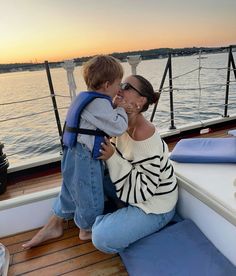 a woman sitting on the back of a boat with a child in her lap,