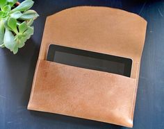 a brown leather case sitting on top of a table next to a plant