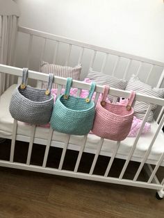 three cribs are lined up in different colors and patterns, one is pink, the other is blue